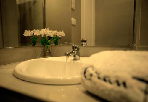 a sink in a bathroom with a mirror and flowers at Hotel Gran Palma Huancayo in Huancayo