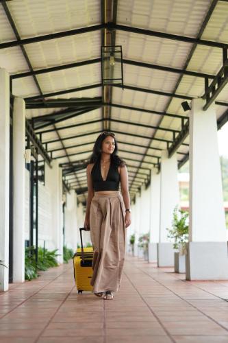 a woman walking with a yellow suitcase in a building at Elephyard Retreat in Mahiyangana