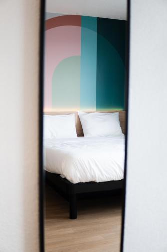 a bed with white sheets and pillows is seen through a mirror at B&B HOTEL Mons Gare in Mons
