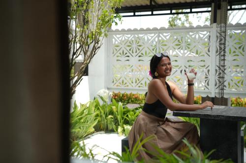 a woman sitting at a table in a garden at Elephyard Retreat in Mahiyangana