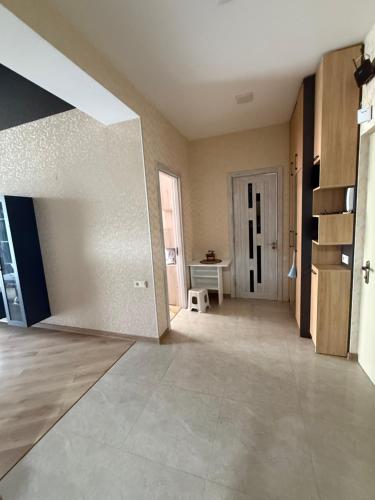 an empty living room with a white wall and a table at Panorama City View Apartment in Tbilisi City