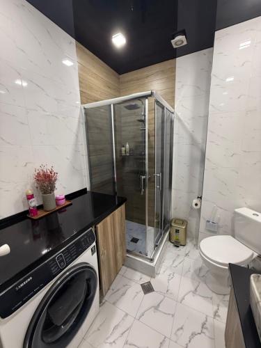 a bathroom with a shower and a washing machine at Panorama City View Apartment in Tbilisi City