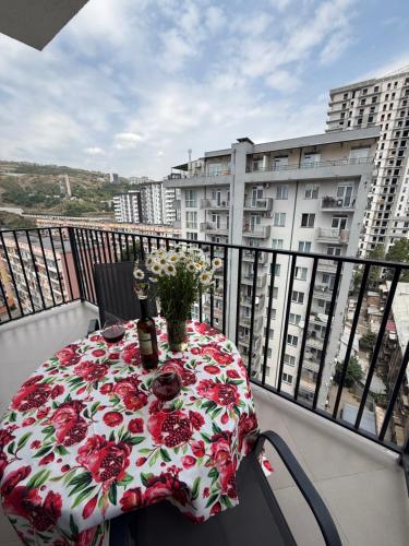 a table with flowers on a balcony with a building at Panorama City View Apartment in Tbilisi City