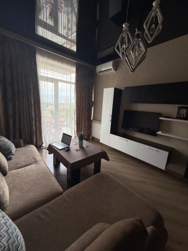a living room with a couch and a table with a laptop at Panorama City View Apartment in Tbilisi City