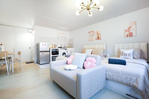 a bedroom with two beds and a couch with pink pillows at Cozy 2BR Near Impact Arena, LTAT- WiFi Washer near DMK at C2 in Ban Song Hong