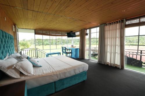 a bedroom with a bed and a balcony with a table at Elephyard Retreat in Mahiyangana
