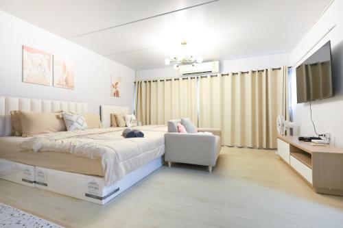 a white bedroom with a large bed and a chair at Cozy 2BR Near Impact Arena, LTAT- WiFi Washer near DMK at C2 in Ban Song Hong