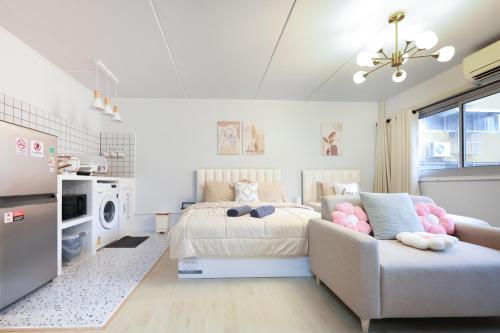 a white bedroom with a bed and a couch at Cozy 2BR Near Impact Arena, LTAT- WiFi Washer near DMK at C2 in Ban Song Hong