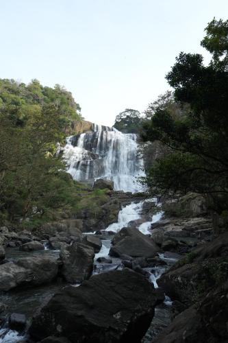 a waterfall in the middle of a river with rocks at Elephyard Retreat in Mahiyangana