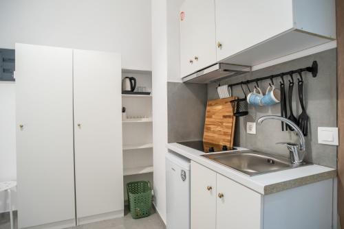 a kitchen with white cabinets and a sink at Olesia Rooms in Naousa in Naousa