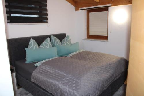 Un dormitorio con una cama con almohadas azules y una ventana. en Ferienwohnung Waldheim, en Greifenburg