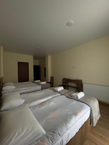 a room with three beds with white sheets at Elnetsa Inn Kazbegi in Stepantsminda