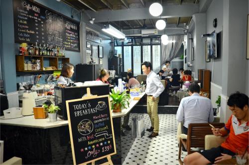 un restaurante con gente sentada en las mesas y un hombre de pie en Goodfellas Thong lo Hostel, en Bangkok