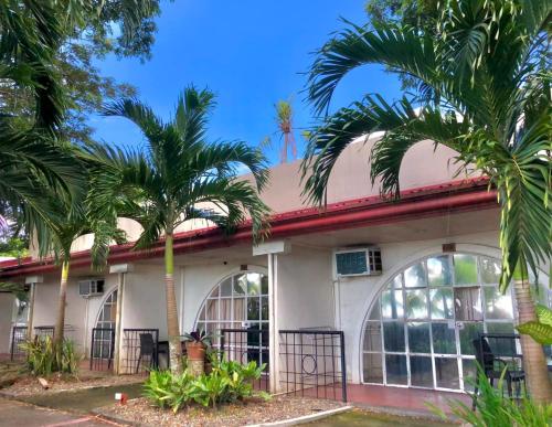 a building with palm trees in front of it at Palmas Del Mar Resort Bacolod in Bacolod