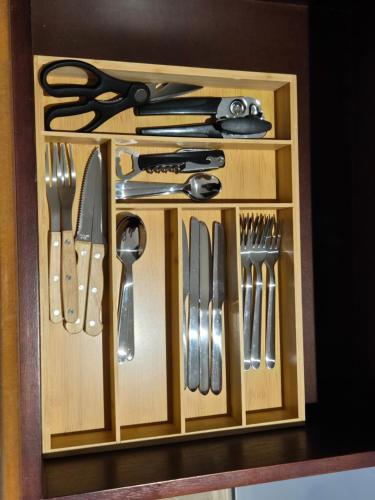 a wooden cabinet filled with knives and utensils at Striped Horse Guest House in Cape Town