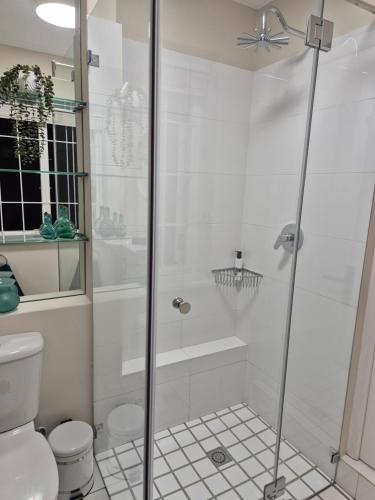 a white bathroom with a shower and a toilet at Striped Horse Guest House in Cape Town