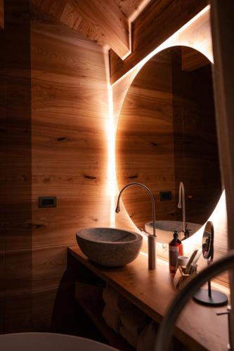 a bathroom with a stone sink and a mirror at Au Charmant Petit Lac - Ecohotel Parc & Spa in Champoluc