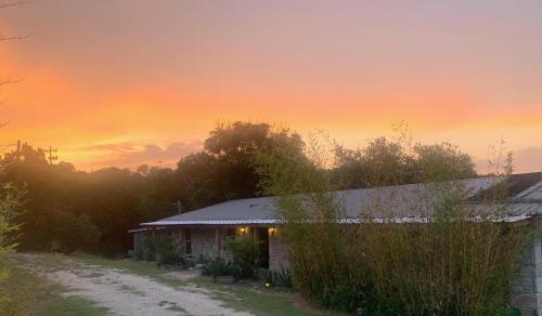 a house in a field with a sunset in the background at La Vista in Canyon Lake