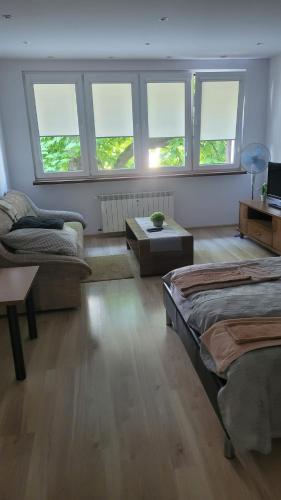 a bedroom with two beds and a table and windows at Mieszkanie Tarnów in Tarnów