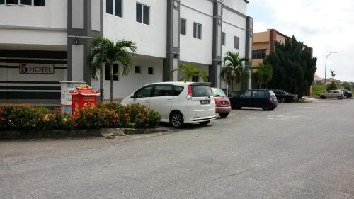un coche blanco aparcado en un aparcamiento al lado de un edificio en Five Hotel en Seremban