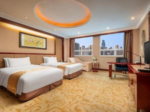a hotel room with two beds and a television at Chutian Guangdong International Hotel in Wuhan