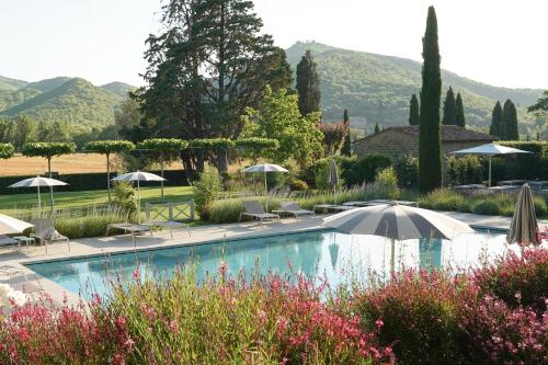 a pool with an umbrella and chairs and umbrellas at Villa di Piazzano - Small Luxury Hotels of the World in Cortona