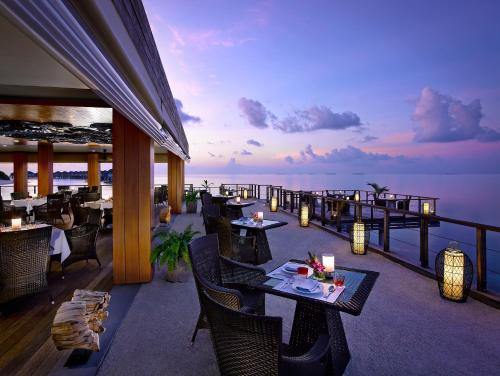 a restaurant with a view of the ocean at dusk at Dusit Thani Maldives - 50 percent discount on transfers for stays until 20 Dec 2025 in Baa Atoll