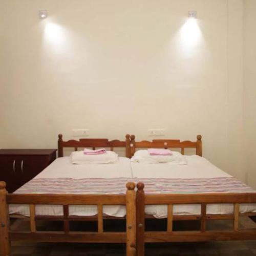 two beds in a bedroom with two lights on the wall at Kadaleevanam Yoga Academy in Cheruvattūr