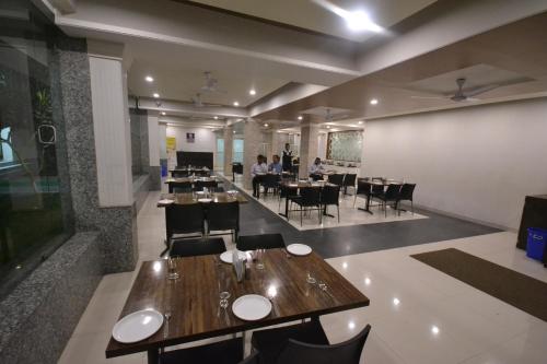 un restaurante con mesas y sillas y gente de fondo en Hotel City Heart Shirdi, en Shirdi