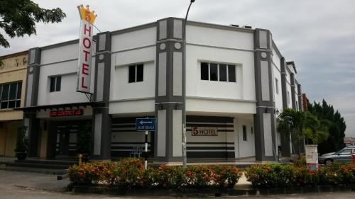 Un edificio blanco con flores delante. en Five Hotel, en Seremban