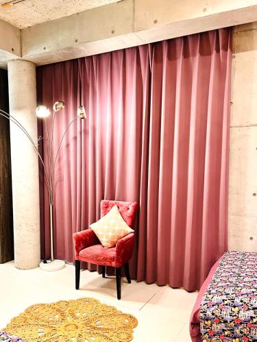a red chair sitting in front of a red curtain at 最大14名 広さ140平米 おもろまち駅免税店3分 国際通り栄町5分 駐車場2台付き casa joshua カーサ ジョシュア in Naha