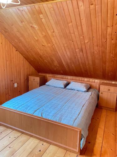 a bed in a cabin with a wooden ceiling at Три смерічки in Beloberëzka