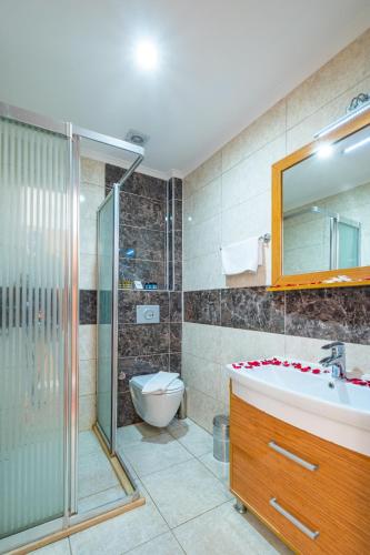 a bathroom with a shower and a sink and a toilet at Tugra Suit Hotel Halal All Inclusive in Alanya