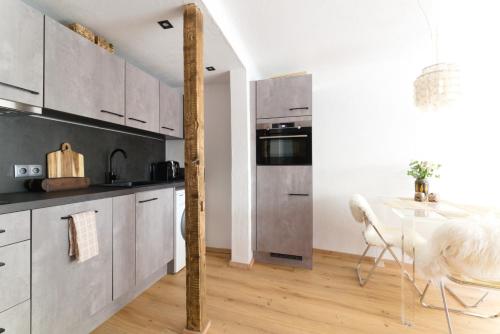 a kitchen with white cabinets and a table with chairs at Cosy & Style Zell am See in Schmitten