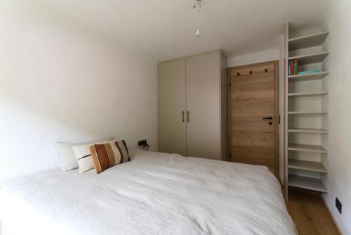 a bedroom with a white bed and a closet at Cosy & Style Zell am See in Schmitten