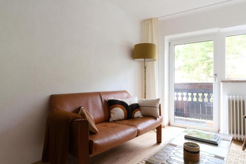 a brown leather couch in a living room with a window at Cosy & Style Zell am See in Schmitten