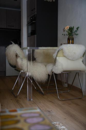a table with white fur chairs and a table with a vase at Cosy & Style Zell am See in Schmitten