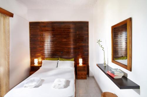 a bedroom with a white bed with a wooden headboard at Sun Nicolas in Kato Daratso