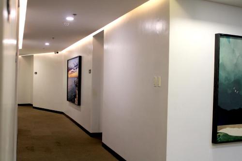 a hallway with white walls and paintings on the walls at Dancenter Boss Hotel Near Clark International Airport in Angeles