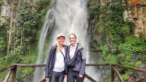 two women standing in front of a waterfall at Nachelle Homestay in Berastagi