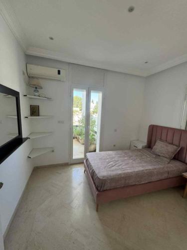 a bedroom with a bed in a white room at Sunny Villa Apartment, 10min Walk to La Marsa Beach in Dar Tahar Zaouch