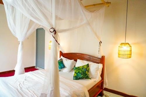 ein Schlafzimmer mit einem Himmelbett mit weißen Vorhängen in der Unterkunft Garden Villa 5BR Home Near Road,Nature and City Life in Arusha