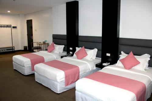 three beds in a hotel room with pink pillows at Dancenter Boss Hotel Near Clark International Airport in Angeles