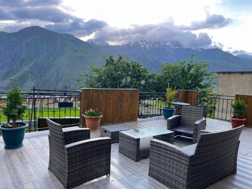 a patio with chairs and a table and mountains at UP Holiday Home in Stepantsminda