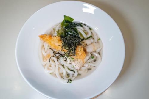 a white plate of food with noodles and seafood at Kritthai Residence in Bangkok