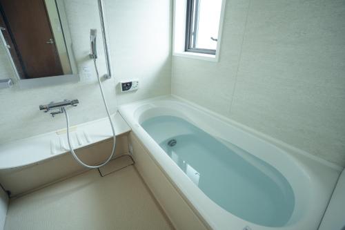Una bañera blanca en un baño con ventana. en Condominium Takabatake, en Nara
