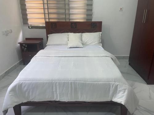 a bedroom with a large bed with white sheets and pillows at Da Palm Inn Abrui in Aburi