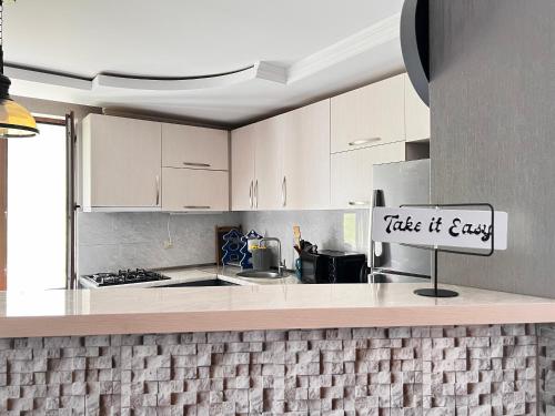 a kitchen with white cabinets and a sign that reads take it easy at UP Holiday Home in Stepantsminda