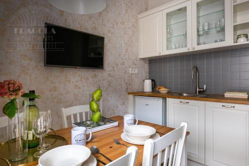 a kitchen with a wooden table and white cabinets at Fragola Apartments Old Town in Kraków