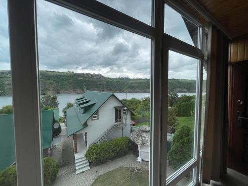 a window with a view of a house and a lake at Family House in Makarovka